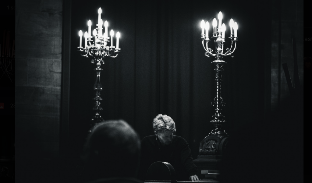 Candlelit organ recital in a cathedral, musician performing between baroque candelabras, black and white photo